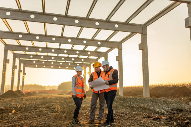 Building contractors analyzing blueprint at construction site Male and female architects discussing over blueprint at construction site land planning stock pictures, royalty-free photos & images