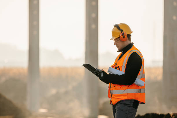 trabajador de la construcción que usa una tableta digital en una obra de construcción - orejeras fotografías e imágenes de stock
