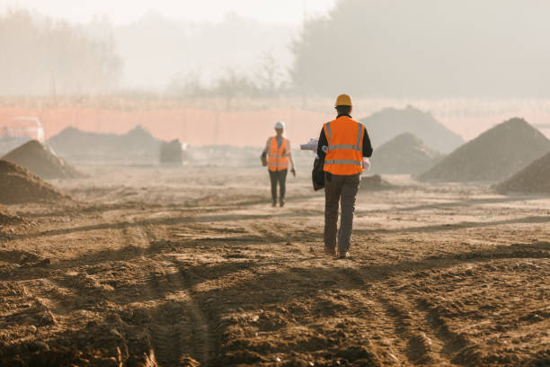 trabajadores de la construcción que evalúan el trabajo en el sitio - mud terrain fotografías e imágenes de stock