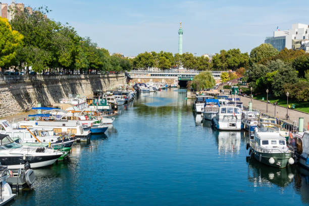 Arsenal boat basin in Paris Paris, France - September 29, 2017. Bassin de l'Arsenal boat basin in Paris. A component of the Parisian Canal Network, it links the Canal Saint-Martin, which begins at the Place de la Bastille, to the Seine, at the Quai de la Rapee. View with boats, toward the Colonne de Juillet and Opera Bastille. st. martins stock pictures, royalty-free photos & images