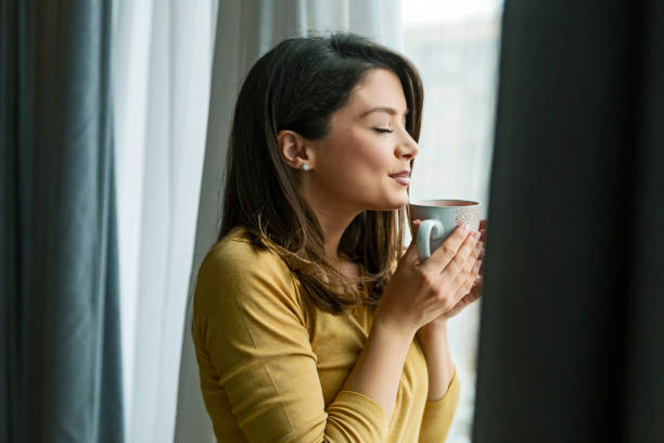 istock Woman with eyes closed drinking coffee looking out the window 1316318139
