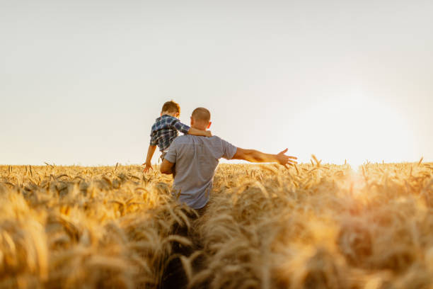 Father and son having fun on field at sunset