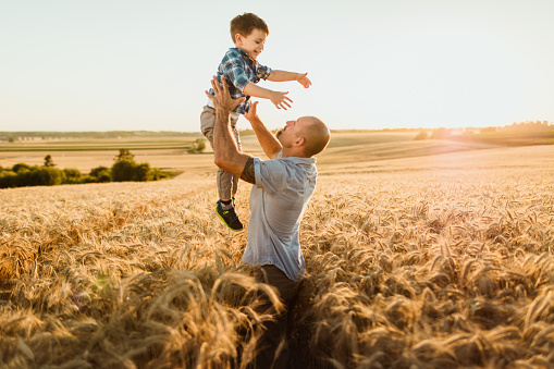 Father playing with son on agricultural field