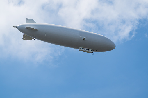 Sky sights, gray airship flying high in blue sky under clouds