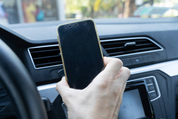 istock Hand of man holding cellphone in car interior 1316329730