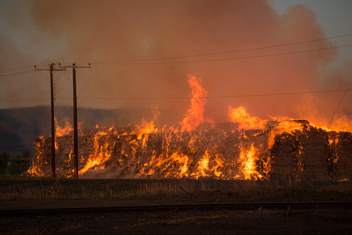 Burning hay stacks 1 ton bales on fire blazing hot with embers flying around lower yakima valley washington state in farm lands
