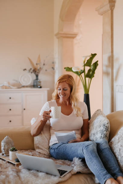 istock Beautiful blond woman enjoying her coffee taking a break during her home office work sitting on the sofa 1316332688