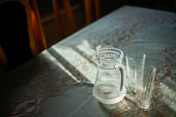 istock Three and empties. Selective focus on glass jug and glasses on the table. Sunset light. Blurred background. 1316333129