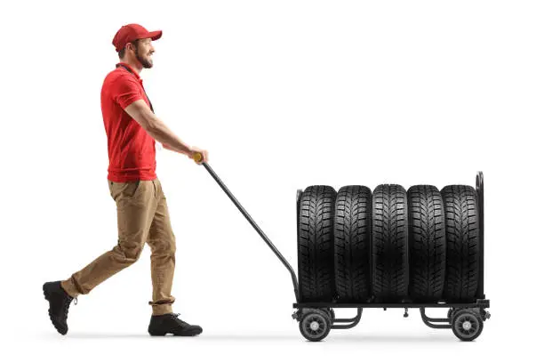 Delivery man pushing a hand truck with tires isolated on white background