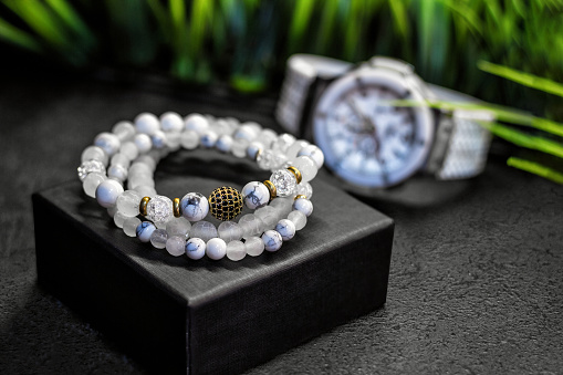 Close-up of luxurious white bracelets made of natural stones and pearls, on a background of watches.