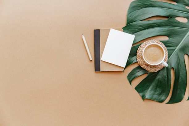 istock A simple trendy office Desk. Coffee cup, monstera leaf, blank card and notebook .Home Office desktop with space copying. Top view, copy space. Minimal concept 1316345372