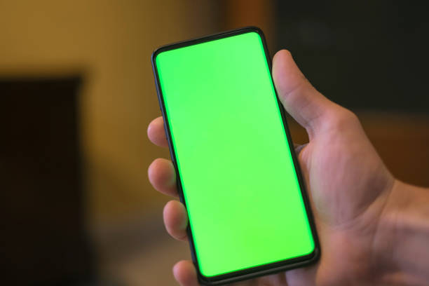 istock Isolated human hand holding a green screen smartphone,hi tech addiction concept 1316347213