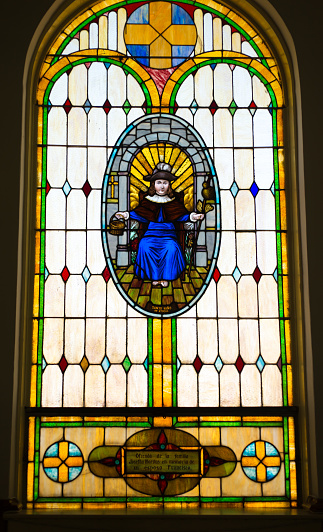 A Ponte Ulla, Spain. Stained glass window representing Saint Mary Magdalene holding cross and a a human skull