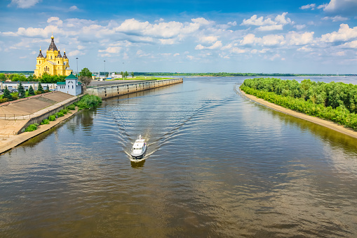 Boat moves on the Oka River in Nizhny Novgorod, Russia with the Alexander Nevsky Cathedral in the background.