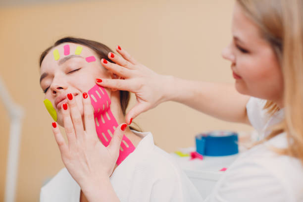 Beautiful woman applying tape lifting treatment on face Beautiful woman applying tape lifting treatment procedure on face corrective action stock pictures, royalty-free photos & images