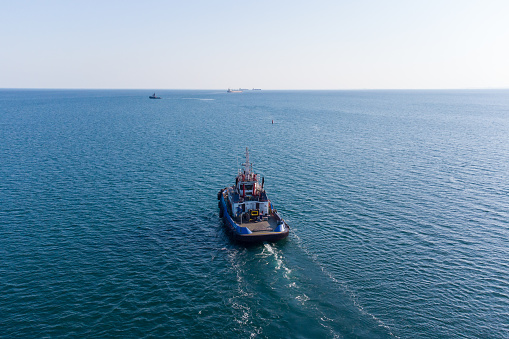 The sea tug moves from the port water area towards the open sea. Photo from the helicopter. View from above.