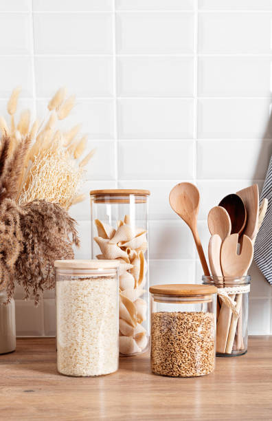 assortment of grains, cereals and pasta in glass jars and kitchen utensils on wooden table - cooking process imagens e fotografias de stock