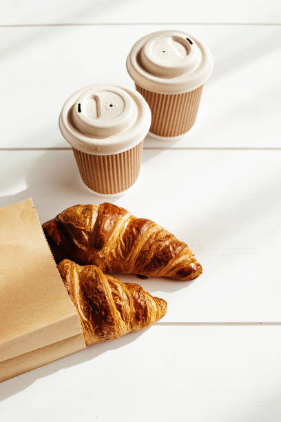 istock Hot coffee on the go and croissants for breakfast. Biodegradable, disposable takeaway cups 1316370180