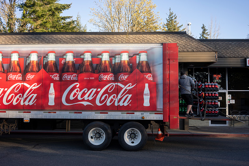 Lake Oswego, OR, USA - Apr 12, 2021: A Coca-Cola delivery driver unloads his truck outside of a Domino's Pizza restaurant in Lake Oswego, Oregon.