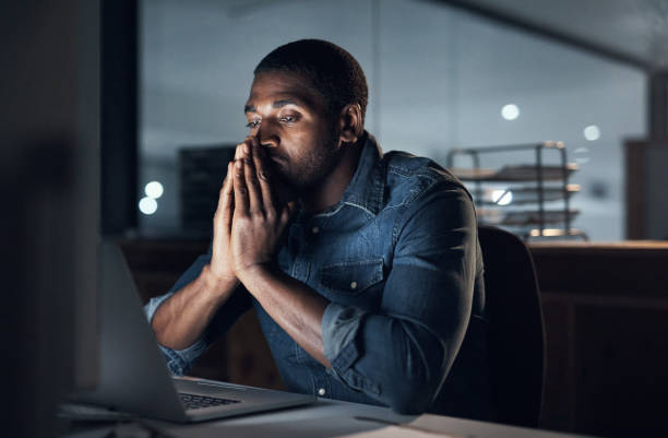 istock Shot of a young businessman looking stressed while using a computer during a late night in a modern office 1316371597