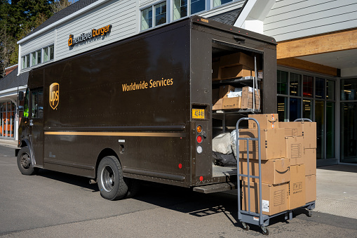 Lake Oswego, OR, USA - Mar 23, 2021: A UPS delivery truck is seen being loaded with returning packages outside of an Amazon hub locker location at a Whole Foods market in Lake Oswego, Oregon.