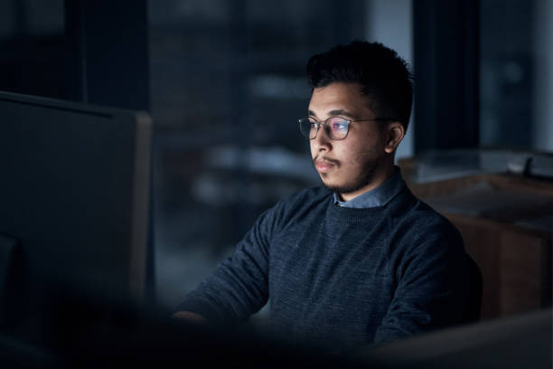 istock Shot of a young businessman using a computer during a late night in a modern office 1316372240