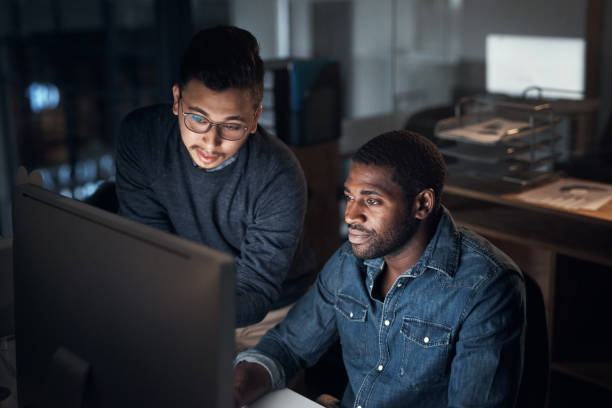 istock Shot of two young businessmen using a computer during a late night in a modern office 1316372251