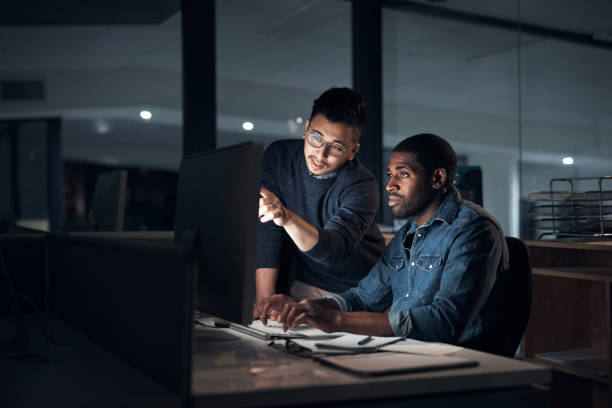 istock Shot of two young businessmen using a computer during a late night in a modern office 1316372252