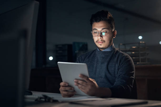istock Shot of a young businessman using a digital tablet and computer during a late night in a modern office 1316372274
