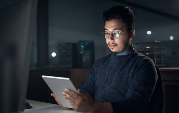 istock Shot of a young businessman using a digital tablet and computer during a late night in a modern office 1316372275