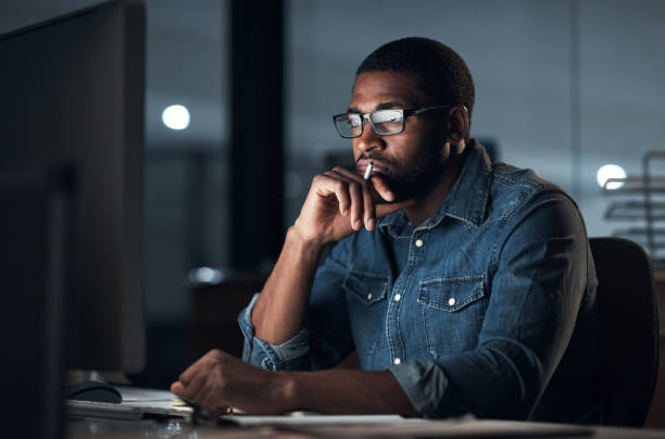 istock Shot of a young businessman using a computer during a late night in a modern office 1316372313