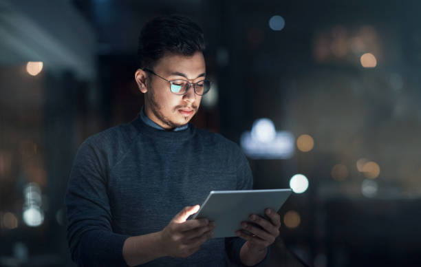 istock Shot of a young businessman using a digital tablet during a late night in a modern office 1316372338