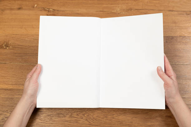 istock Woman's hands open empty catalog, magazines, book mockup on wooden table 1316384286