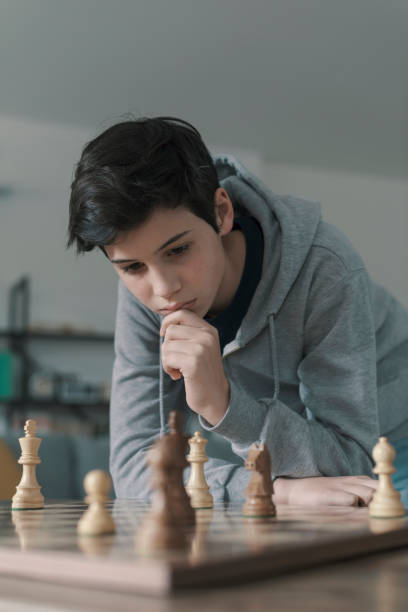 istock Smart boy playing chess and staring at the chessboard 1316385881