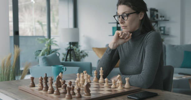 istock Woman playing chess at home 1316386628