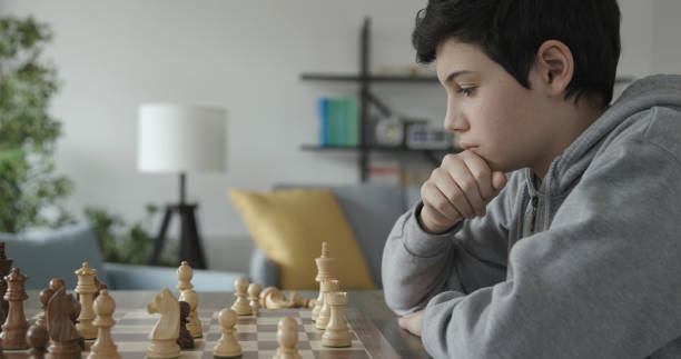 istock Smart boy playing chess and staring at the chessboard 1316386911