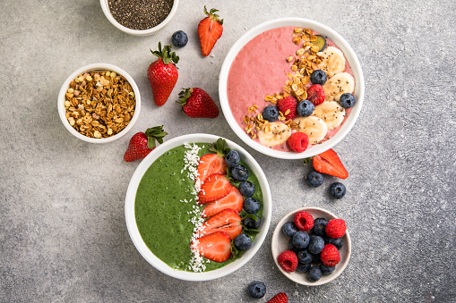 Matcha green tea breakfast superfoods smoothies bowl topped with strawberries, blueberries, coconut flakes Overhead, top view, flat lay