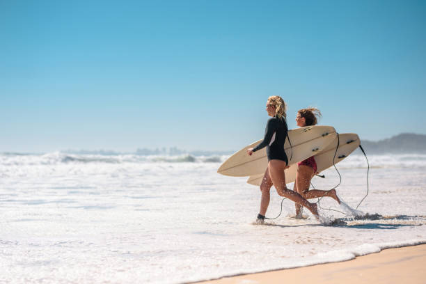 istock Young Female Surfers Walking with Boards into Waves 1316390083