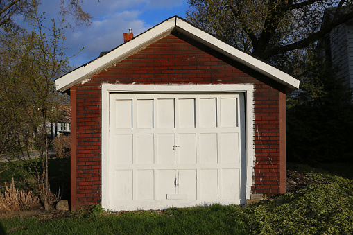 White Garage door on a shed car park door. Shed stock photo with white door. Brick shed with white door and copy space.