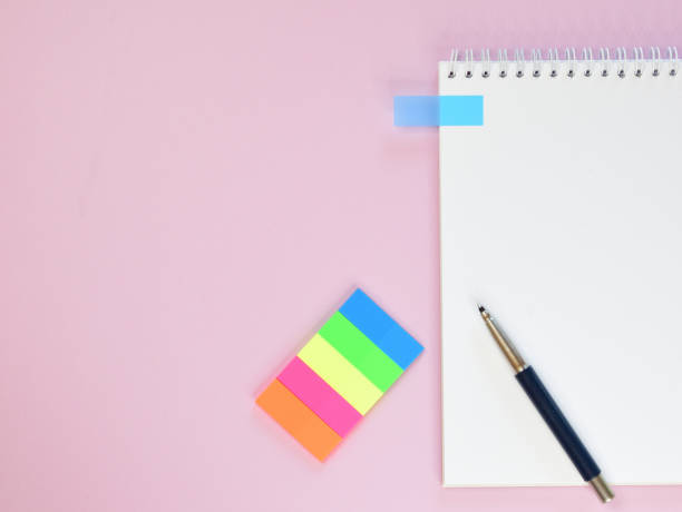 istock Blank page of a spring notepad with an attached sticker for notes. There is a pen on the notepad and a set of colored stickers next to it. 1316393259