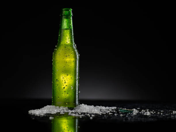istock Ice Cold Green Beer Bottle Covered with water drops - condensation. Blank for drink beverage product design mock-up.  Standing on black table with dark - black background. 1316396793