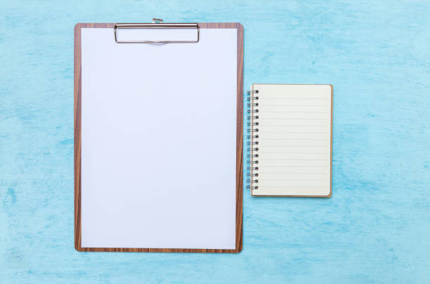 istock Wooden clipboard with blank paper white paper and notebook on blue texture background, blank paper sheet 1316397413