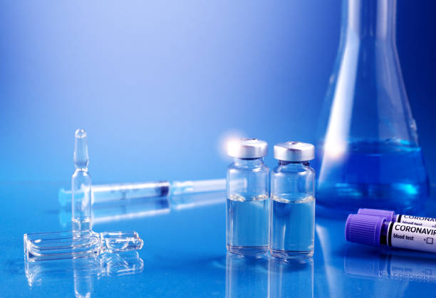 istock Glass ampoules with liquid for injection against laboratory flasks on dark background. Vaccination from coronavirus Covid-19 theme 1316397443