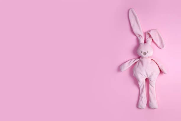 Cute pink plush rabbit on pink background with copy space