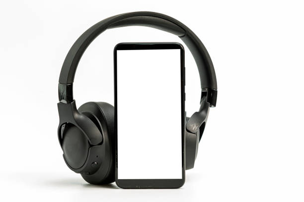 headphones with Bluetooth technology on white background, with black phone paired for music lovers black wireless headphones and smartphone on white background, blank screen mockup, copy space podcast mobile stock pictures, royalty-free photos & images