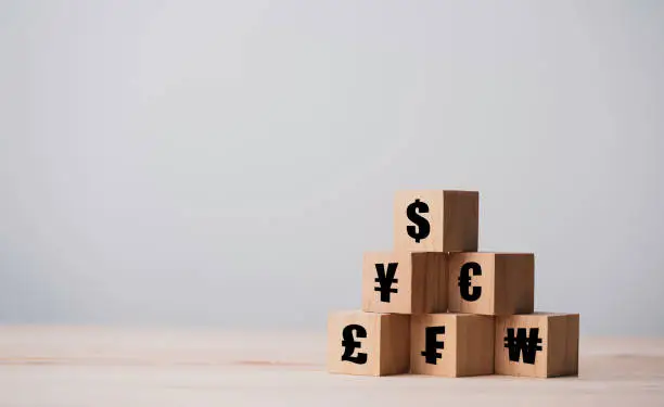 Photo of Wooden cube of US dollar sign to Renminbi Yuan  Yen Euro and Pound sterling sign.US dollar is main and popular currency of exchange in the world.Investment and saving concept.