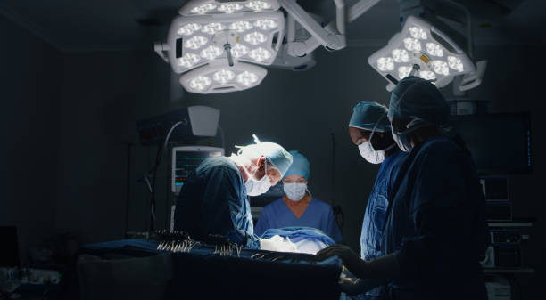 shot of a medic team performing surgery in theatre - surgeon imagens e fotografias de stock