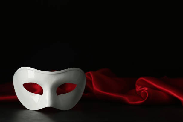 istock White theatre mask and red fabric on black background, space for text 1316404854