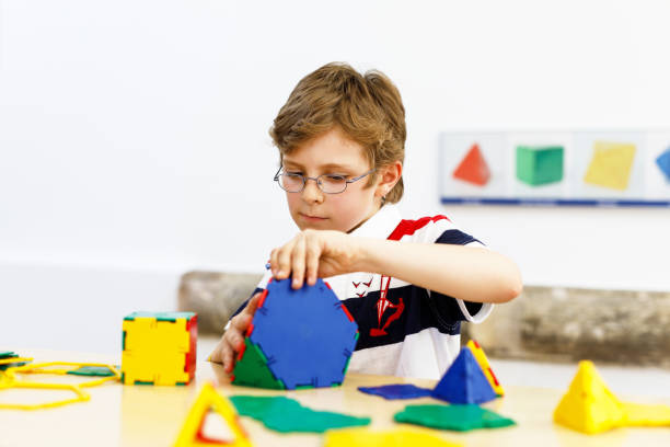 istock Happy kid boy with glasses having fun with building and creating geometric figures, learning mathematics and geometry 1316404869