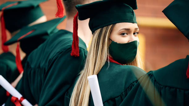 istock Smiling female student wearing protective face mask on her graduation day and looking at camera. 1316404873